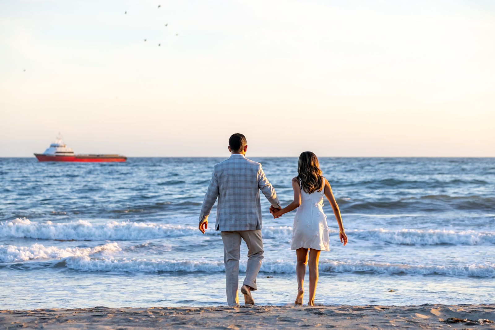Ria and Sunder walking hand in hand into the waves
